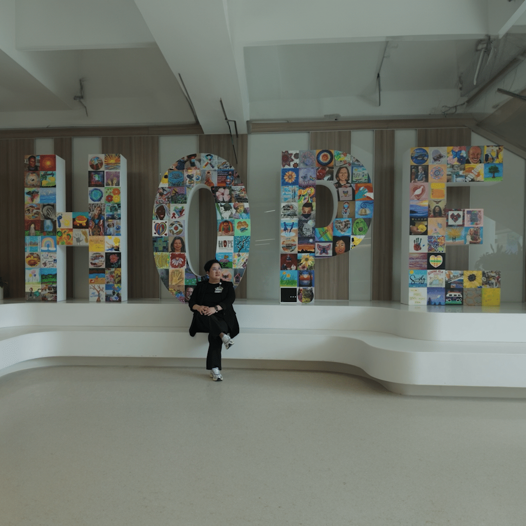 A person sitting in front of a Hope sign.